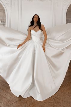 a woman in a white wedding dress is posing for the camera