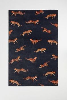 a black and orange wall hanging with leopards on it's side, in front of a white wall