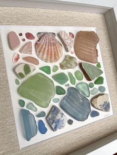 sea glass and seashells are displayed in a shadow box