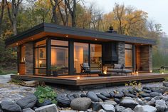 a small cabin is lit up by candles on the porch and patio area next to some rocks