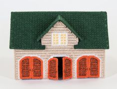 a small house made out of knitted material with an orange door and green roof