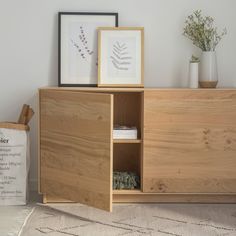 a wooden cabinet sitting on top of a rug next to a vase with flowers in it