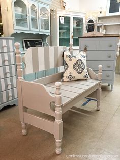 a white bench sitting in the middle of a room next to dressers and cabinets