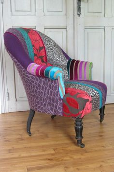 a colorful chair sitting on top of a hard wood floor next to a white door