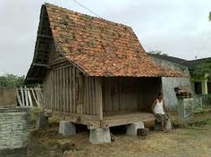 a man sitting on a bench in front of a wooden building with a red tile roof