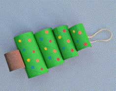 four rolls of toilet paper wrapped in green and multicolored polka dot paper, tied with twine