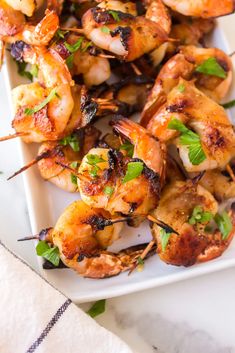 grilled shrimp skewers on a white platter with garnishes