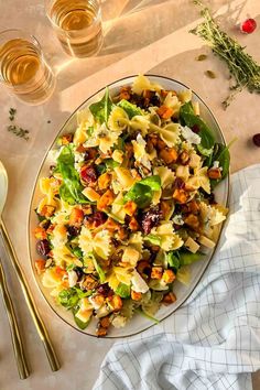 a plate filled with pasta salad on top of a table next to glasses and silverware