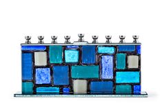 PRICES MAY VARY. HANDCRAFTED GLASS WALL: Silver candle holders stand atop a wall of glass with aqua, turquoise, cerulean blue, navy & white “stones” resembling the Kotel to make this glass menorah an artwork. A TIMELESS TRADITION: The contemporary menorah features a wall design with a twist of color. It meets all halachic requirements. Celebrate the holiday and light up the night! QUALITY CRAFTED: Made with premium grade materials, and high quality construction, our menorahs for chanukah stand s Glass Menorah, Chanukah Menorah, Silver Candle Holders, Hanukkah Candles, Standing Candle Holders, Silver Candle, Jewish Culture, Western Wall, Hanukkah Menorah