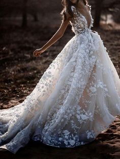 a woman in a wedding dress is walking through the sand with her hand on her hip