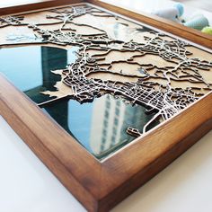 a wooden frame with a cut out city map on the front and bottom, sitting on a table