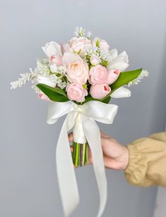 a person holding a bouquet of white and pink flowers