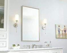 a bathroom vanity with two lights and a painting on the wall next to it's mirror