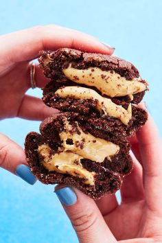 a chocolate cookie sandwich with peanut butter frosting on the top is being held by a woman's hand