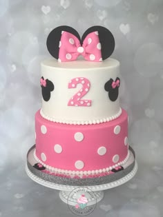 a pink and white cake with minnie mouse ears on top