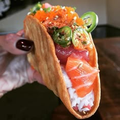 a person holding up a taco filled with lots of toppings on top of rice