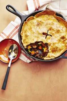 a pot pie with a cross on the side and a spoon next to it sitting on a table