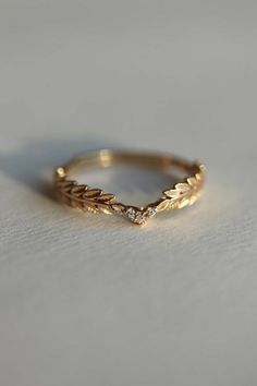 a gold ring with leaves and diamonds on the inside, sitting on a white surface