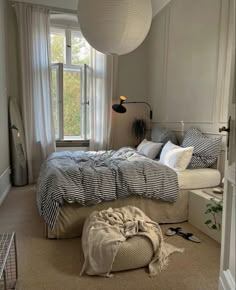 a bedroom with a large bed and lots of pillows on the floor in front of a window