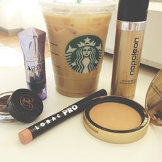 various cosmetics and makeup products sitting on a table next to a cup of starbucks coffee