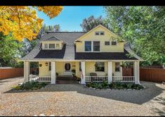 a yellow house with black roof and white trim