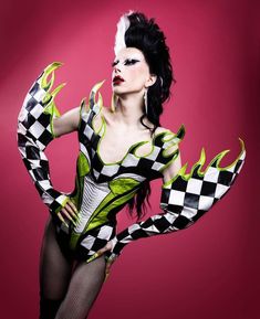 a woman with black and white makeup is posing for a photo wearing a checkered costume