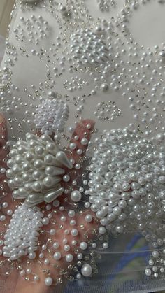 a person holding beads in their hand with white pearls all over the top of them