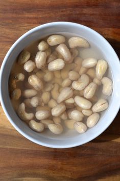 a white bowl filled with beans on top of a wooden table