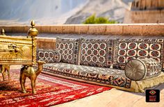 an ornately decorated couch sitting on top of a rug next to a golden chest