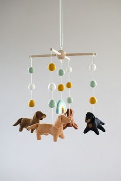 three stuffed animals hanging from a mobile in the shape of birds, dogs and circles