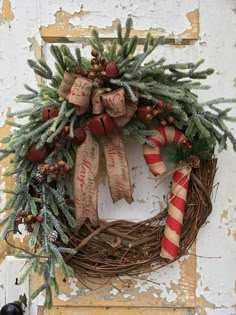 a christmas wreath hanging on the side of a door with candy canes and pine cones