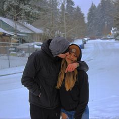 a man and woman standing in the snow with their hands on each other's shoulders