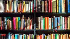 a book shelf filled with lots of colorful books next to a wall full of books