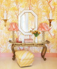 a table with a mirror and lamps on it in front of a wallpapered room