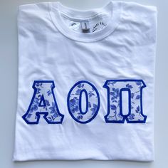 a white t - shirt with blue letters that spell aoi and flowers on it