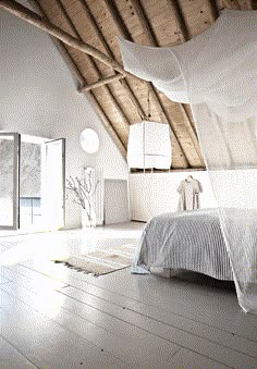 a white bed sitting under a wooden ceiling