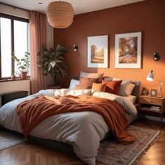 a bedroom with orange walls and wooden flooring is furnished with a large bed that has an orange blanket on it