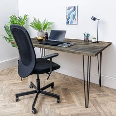 a desk with a laptop on it and a plant in the corner next to it