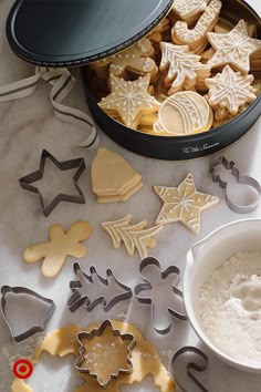 cookie cutters and cookies on a table next to a bowl of powdered sugar