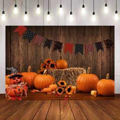 pumpkins, hay bales and sunflowers are arranged on the wooden floor