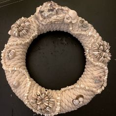 a wreath made out of rope and shells on a black surface with other items around it