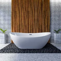 a white bath tub sitting on top of a stone floor next to a bamboo wall