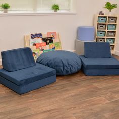 a living room with blue furniture and bookshelves on the floor in front of a window