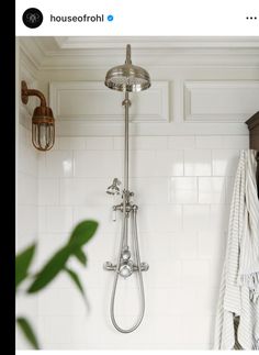 a shower head and hand held shower faucet in a bathroom with white tile walls