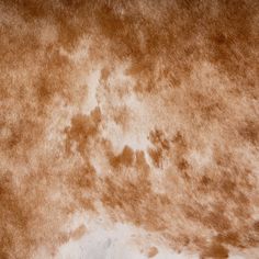 a brown and white cow skin textured with some light brown spots on it's side