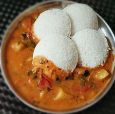 three rice balls sit on top of some curry in a silver bowl with other food items