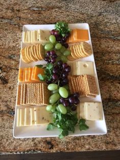 grapes, cheese and crackers are arranged on a plate