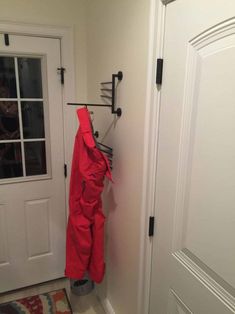 a red jacket hanging on a coat rack next to a white door