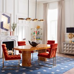 an elegant dining room with red chairs and a round table in front of a fireplace