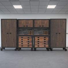 an empty room with two large wooden cabinets on casteors and three smaller wood drawers